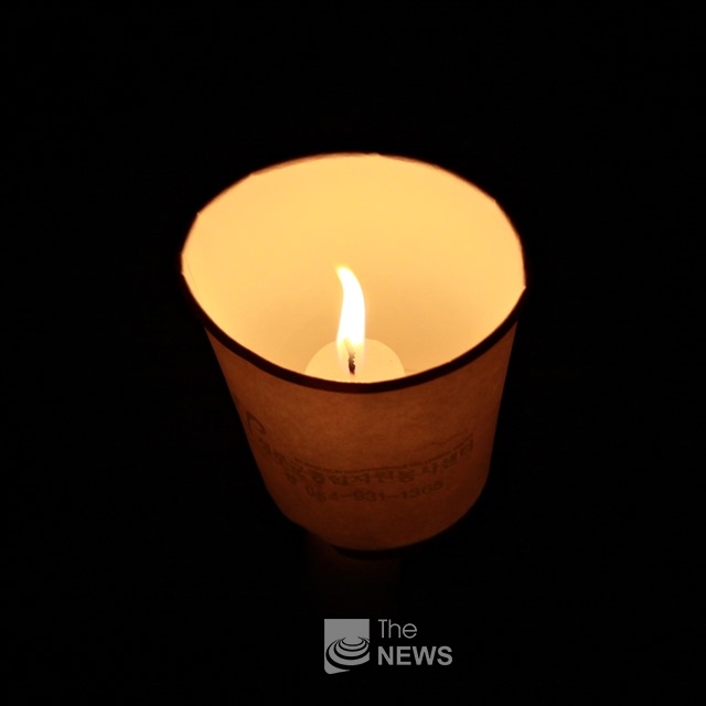 촛불집회에 참석한 한 어린아이가 자신의 초에 불을 밝혔다. <사진 김재봉 기자>