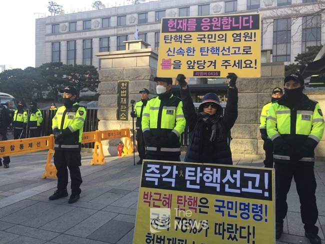 헌법재판소 정문 앞에서 시민이 탄핵을 촉구하는 피켓을 들고 서 있다. <노부호 기자>